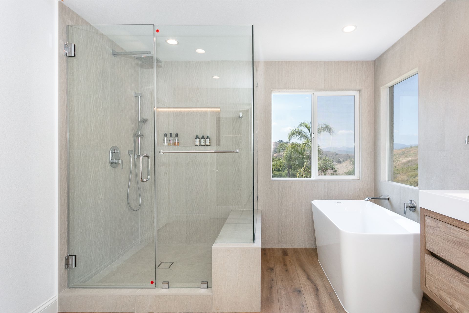 Modern bathroom with a glass shower, soaking tub, and wooden floors.