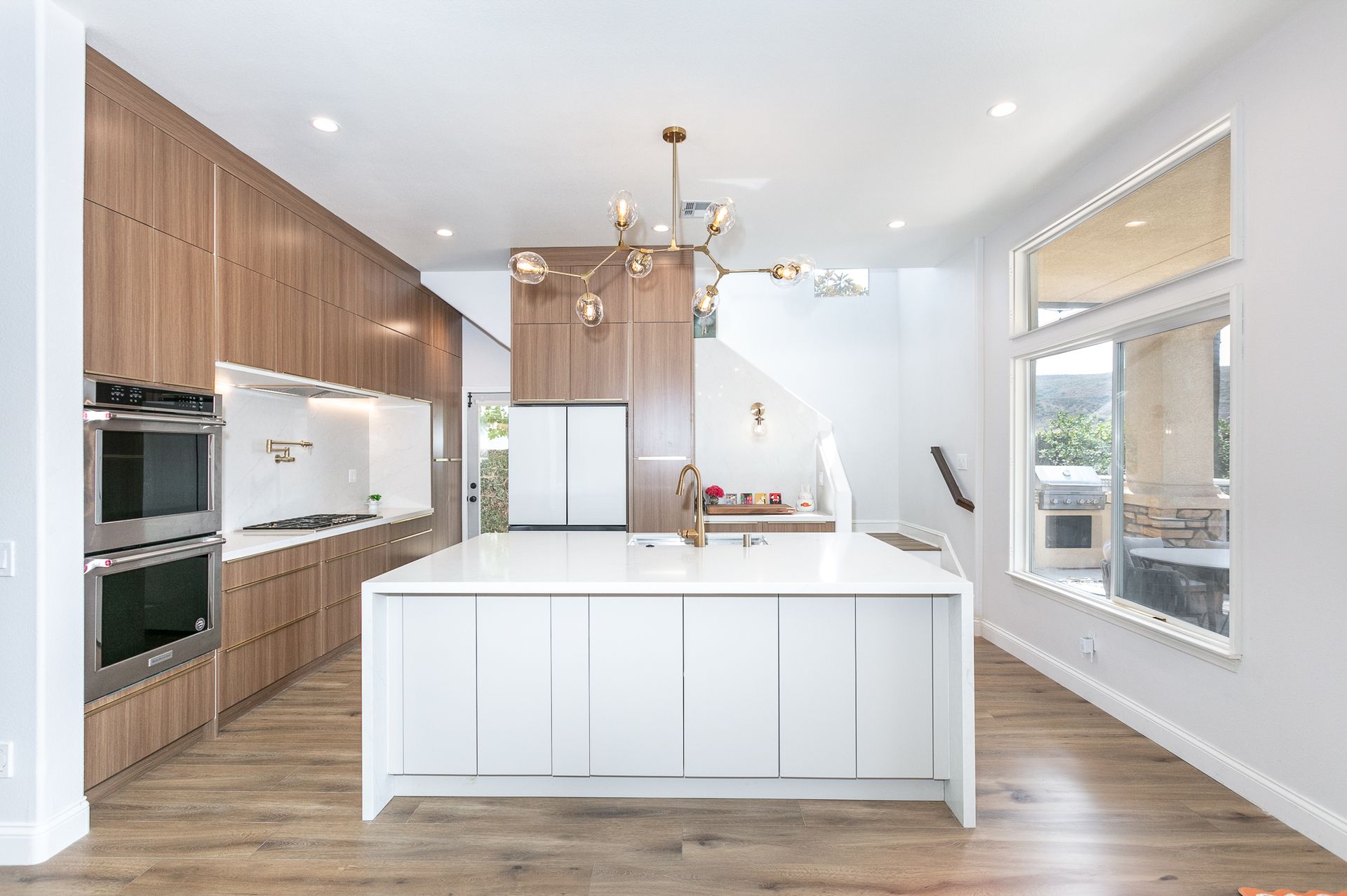 Modern kitchen with wood cabinets, white island, and large window.