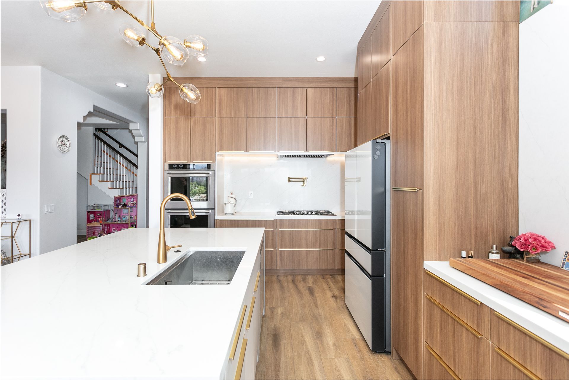 Modern kitchen with wood cabinets, white countertops, stainless steel appliances, and gold accents.