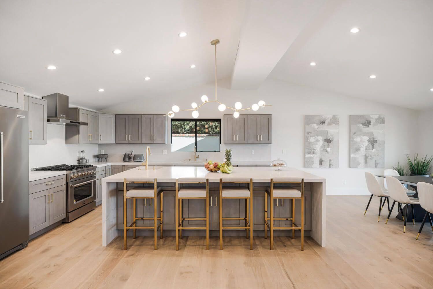 Modern kitchen with light wood floors, gray cabinets, and a large island with seating.