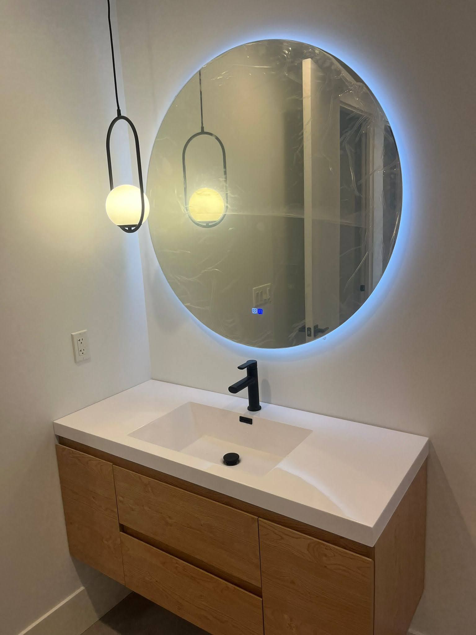Gust bathroom with a floating vanity, round mirror, and trendy lighting.