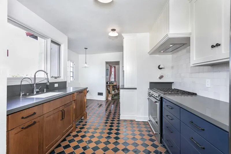 Kitchen with checkered floor, wood cabinets, blue lower cabinets, white uppers, and stainless steel appliances.