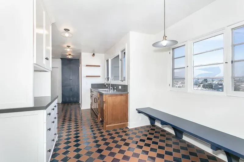Kitchen with checkered floor, wooden cabinets, bench seating by windows.