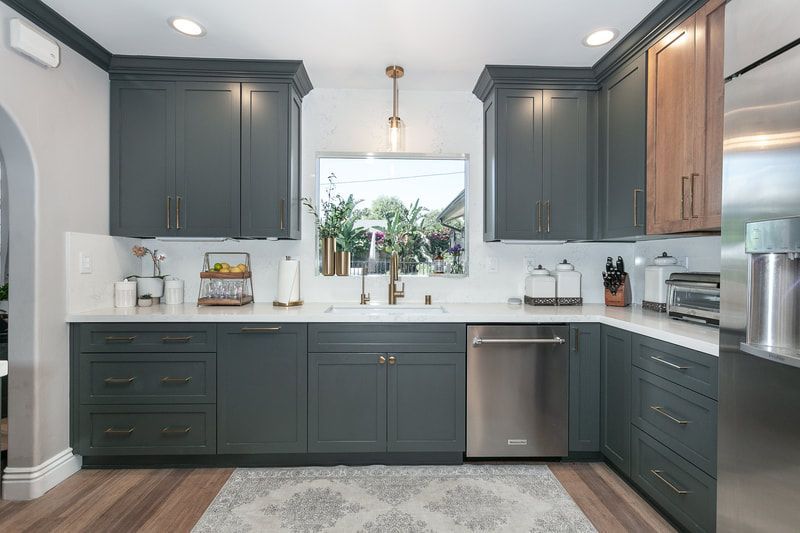Gray and white kitchen with dark cabinets, stainless steel appliances, and a window over the sink.