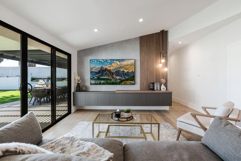 Modern living room with a mounted TV, floating cabinet, and large glass sliding doors leading to a patio.