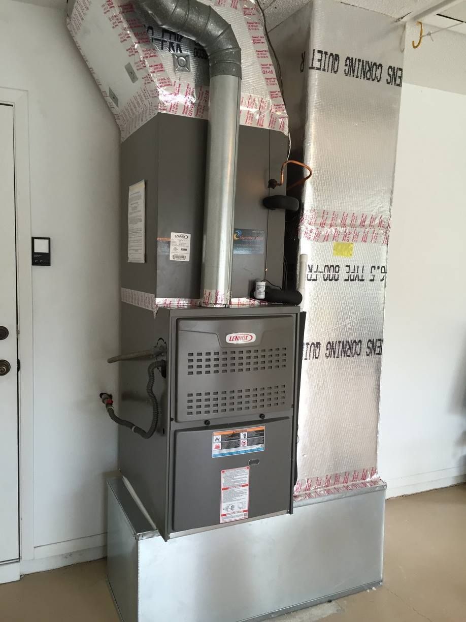 A tall, gray Lennox furnace with ductwork in a garage setting