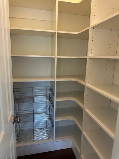 Empty white closet with built-in shelves and hanging rods, plus a wire basket on the lower left.