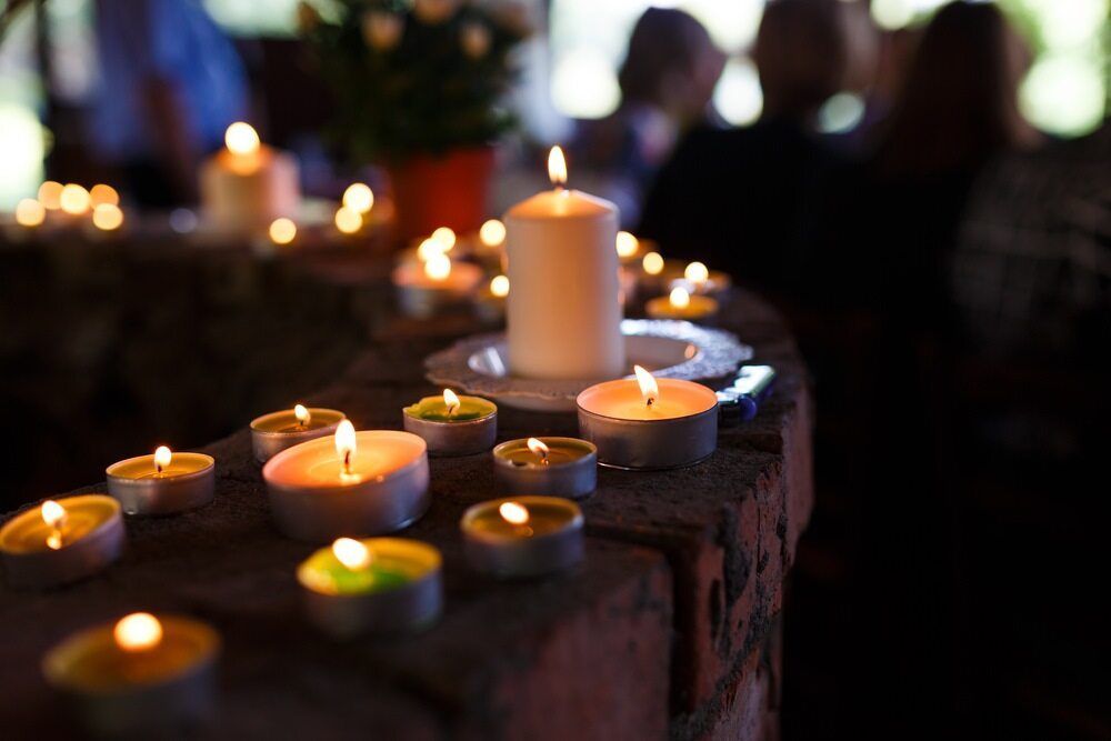 A Bunch of Lit Candles Are Sitting on a Brick Wall — Bull Family Funerals in Warialda, NSW
