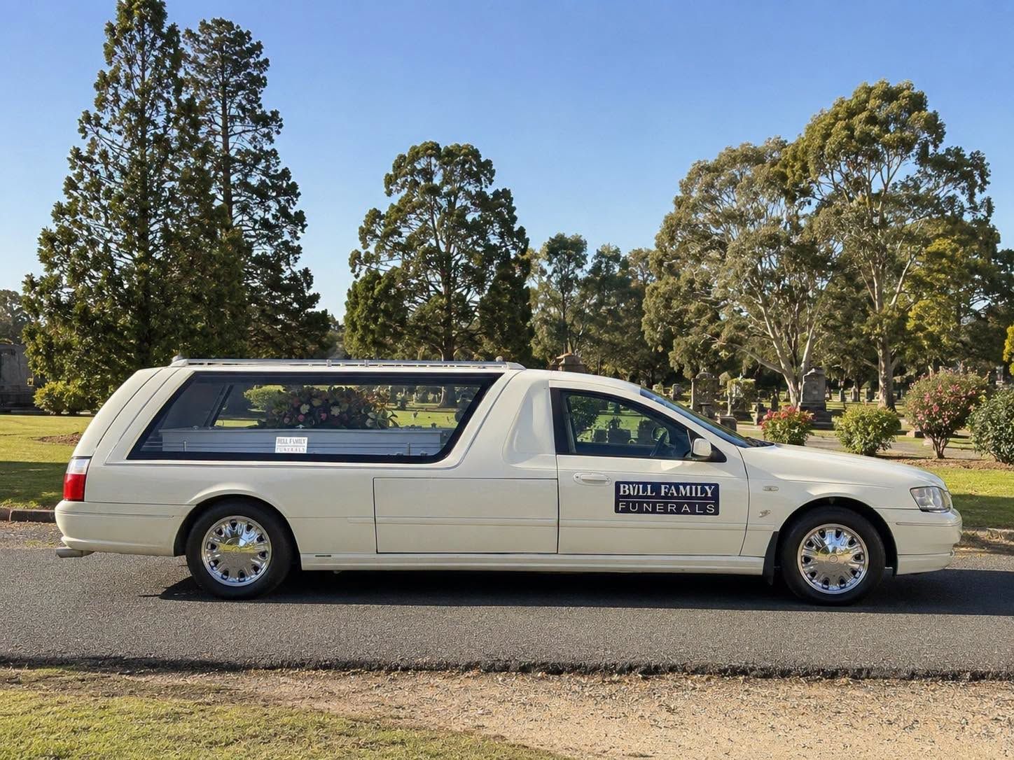 White car parked on a road beside trees on a sunny day — Bull Family Funerals in Warialda, NSW