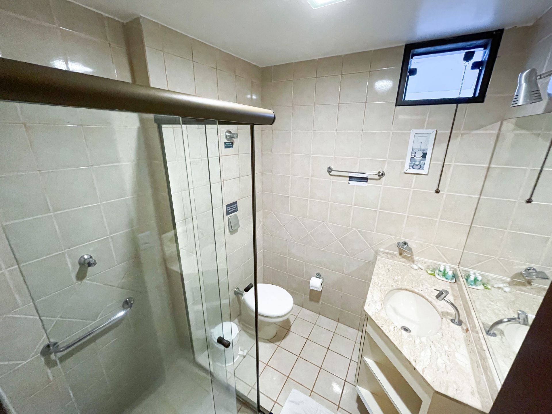 A bathroom with a toilet , sink and shower.