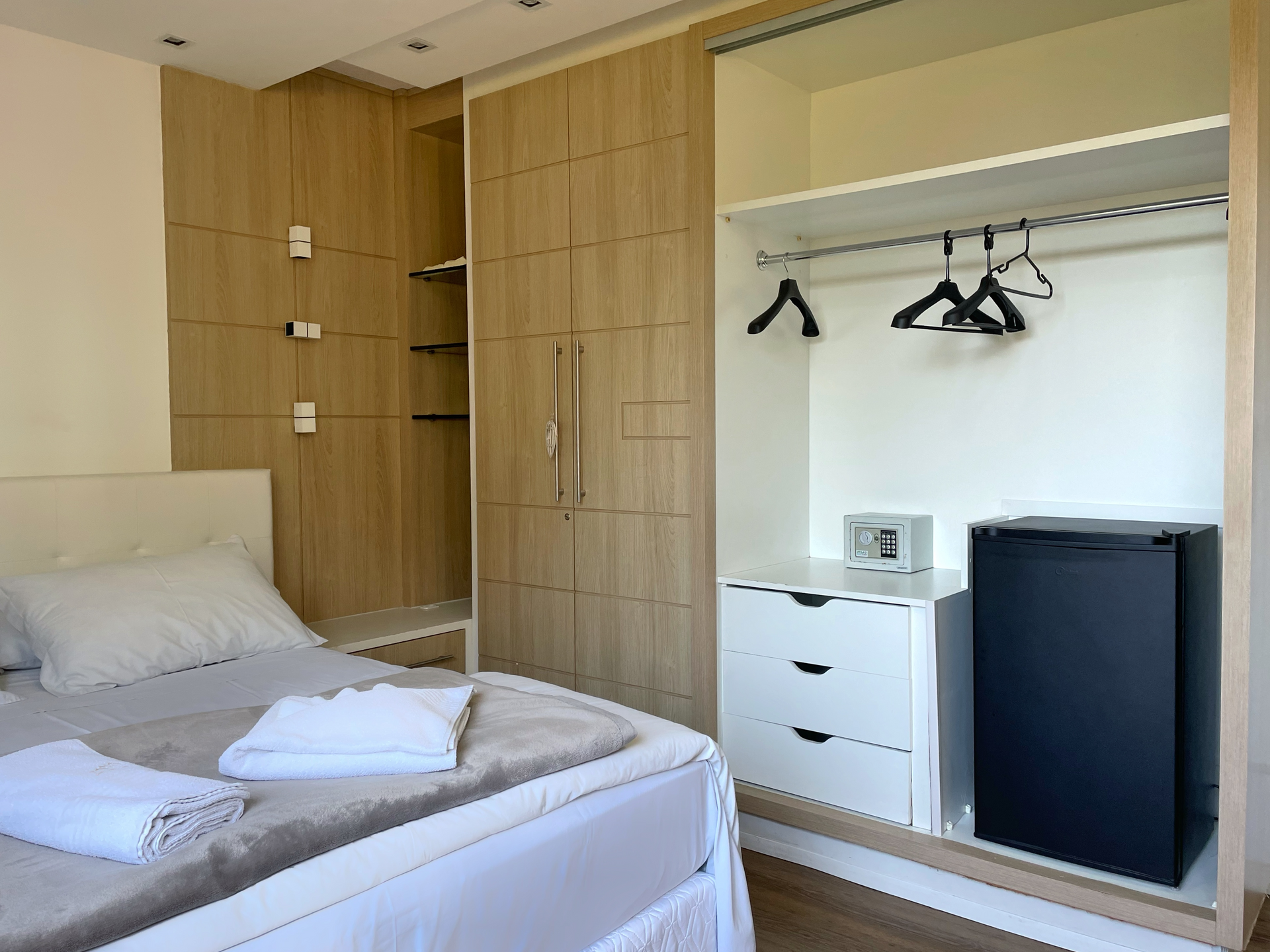 A hotel room with a bed , dresser , refrigerator and closet.