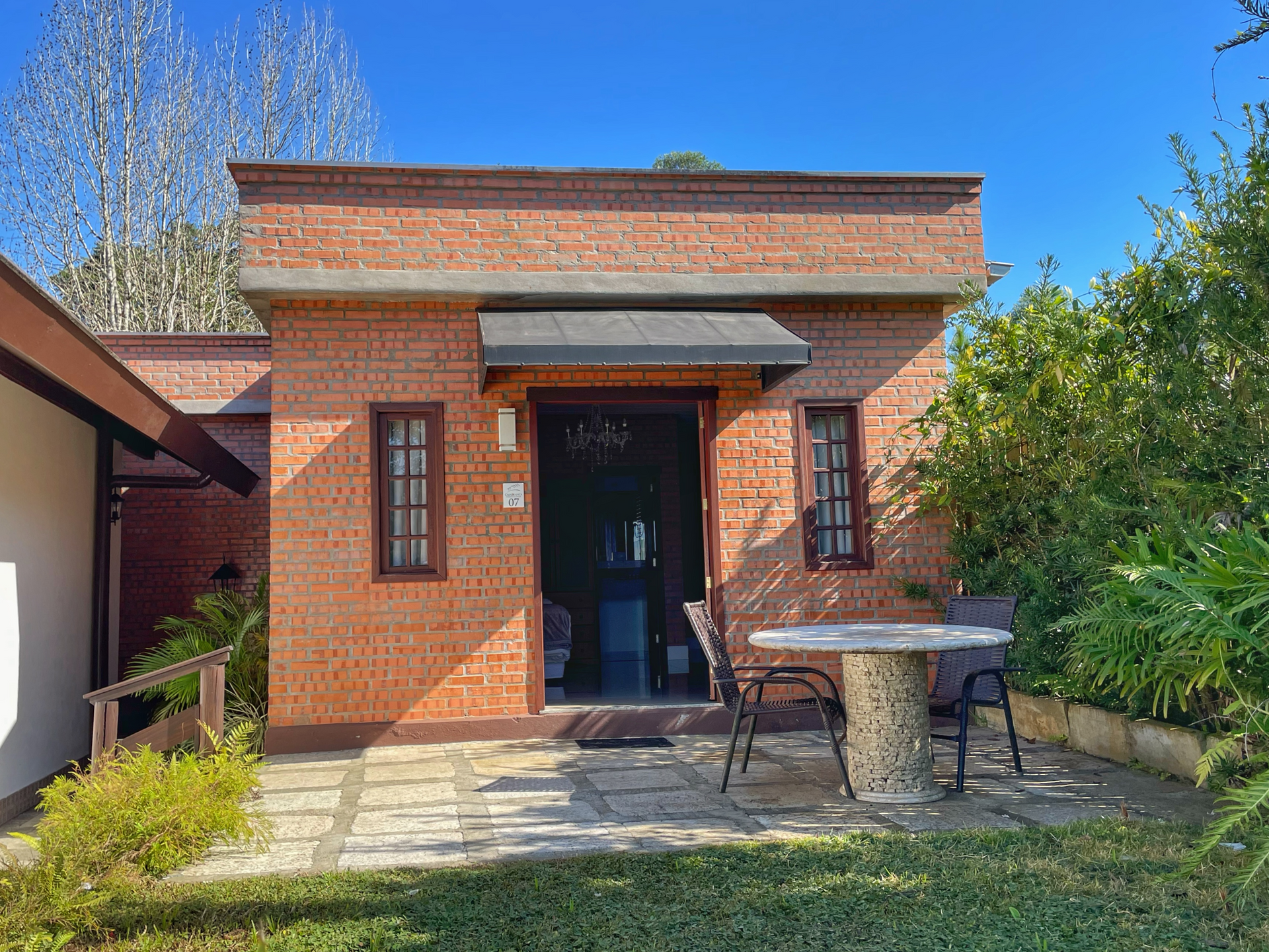 A small brick house with a table and chairs in front of it.
