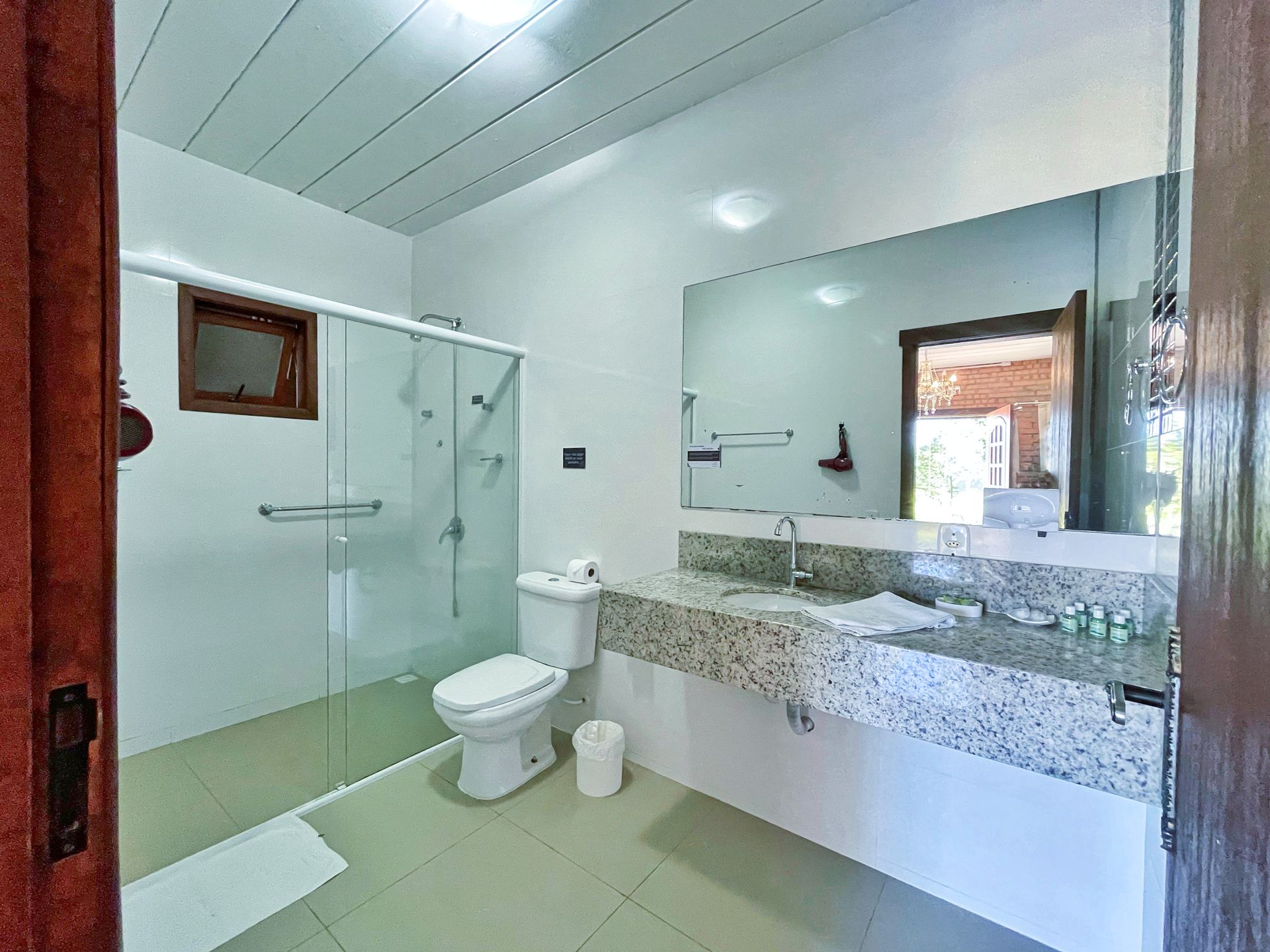 A bathroom with a toilet , sink , shower and mirror.