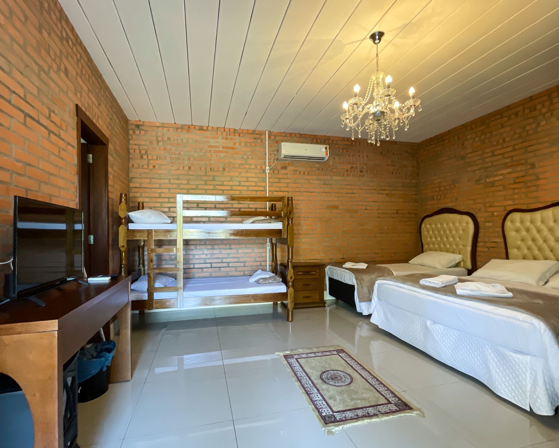 A hotel room with bunk beds , two beds , a desk and a television.