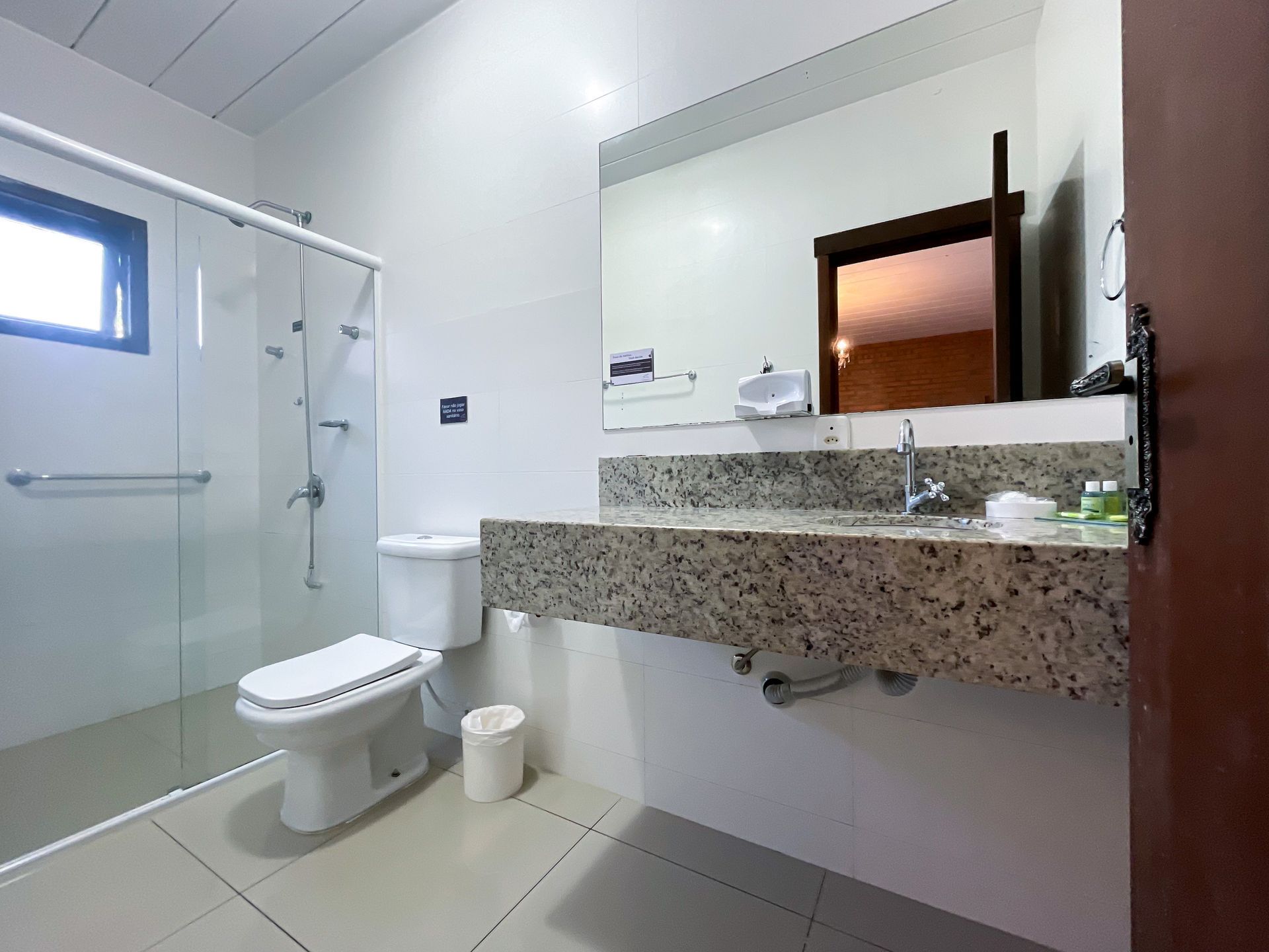 A bathroom with a toilet , sink , shower and mirror.