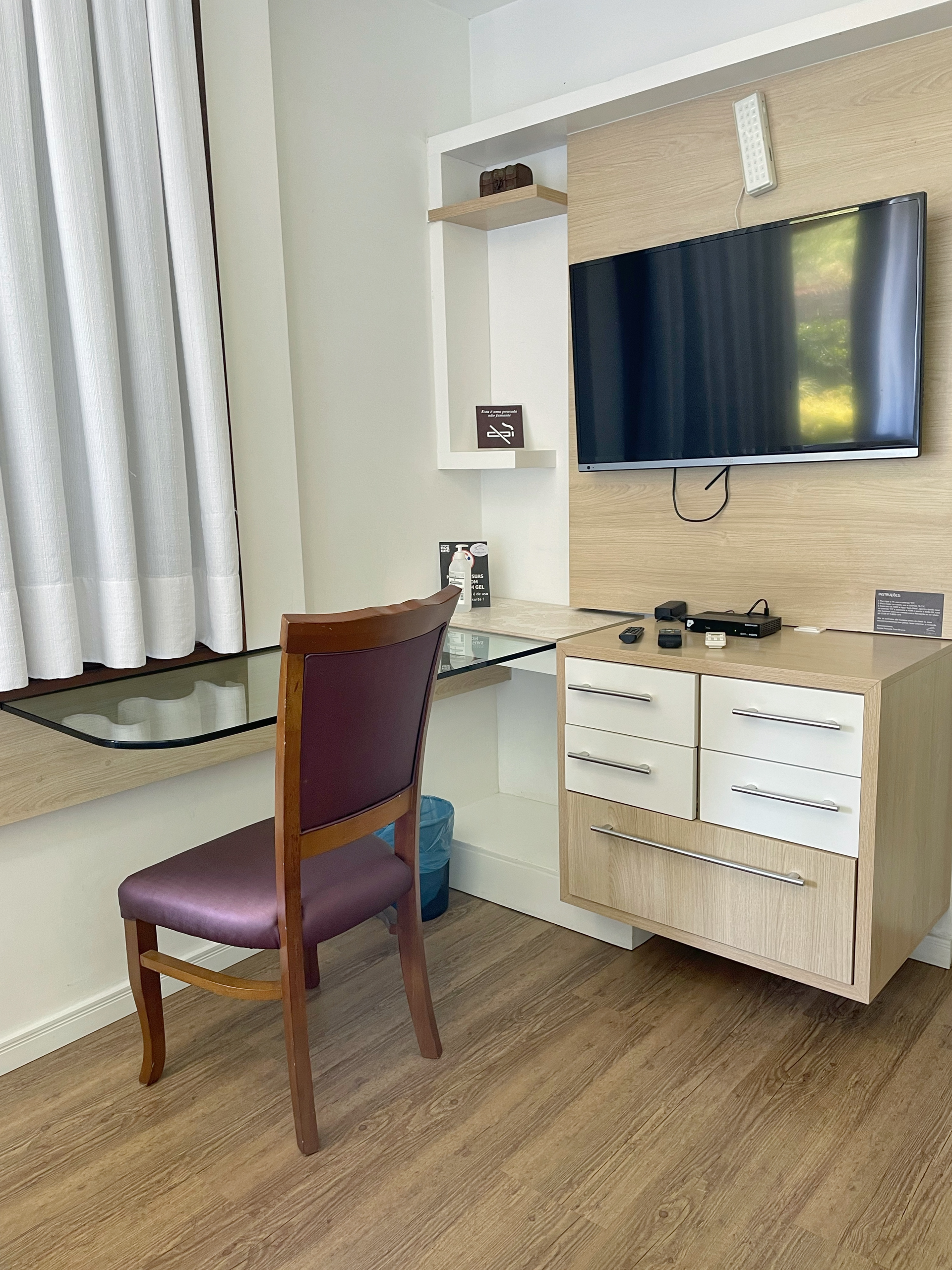 There is a desk with a chair and a television on the wall.