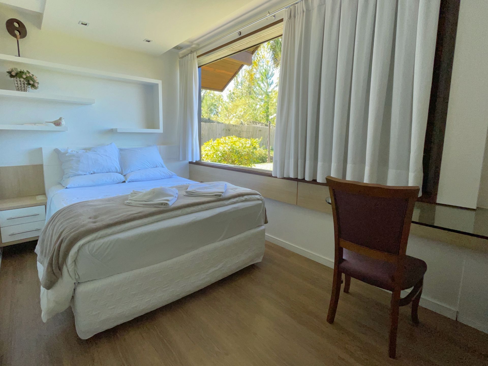 A bedroom with a bed , chair , desk and window.