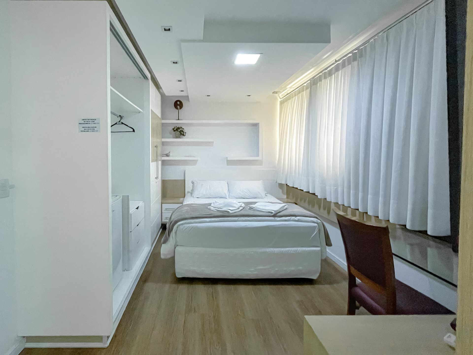 A hotel room with a bed , desk and chair.