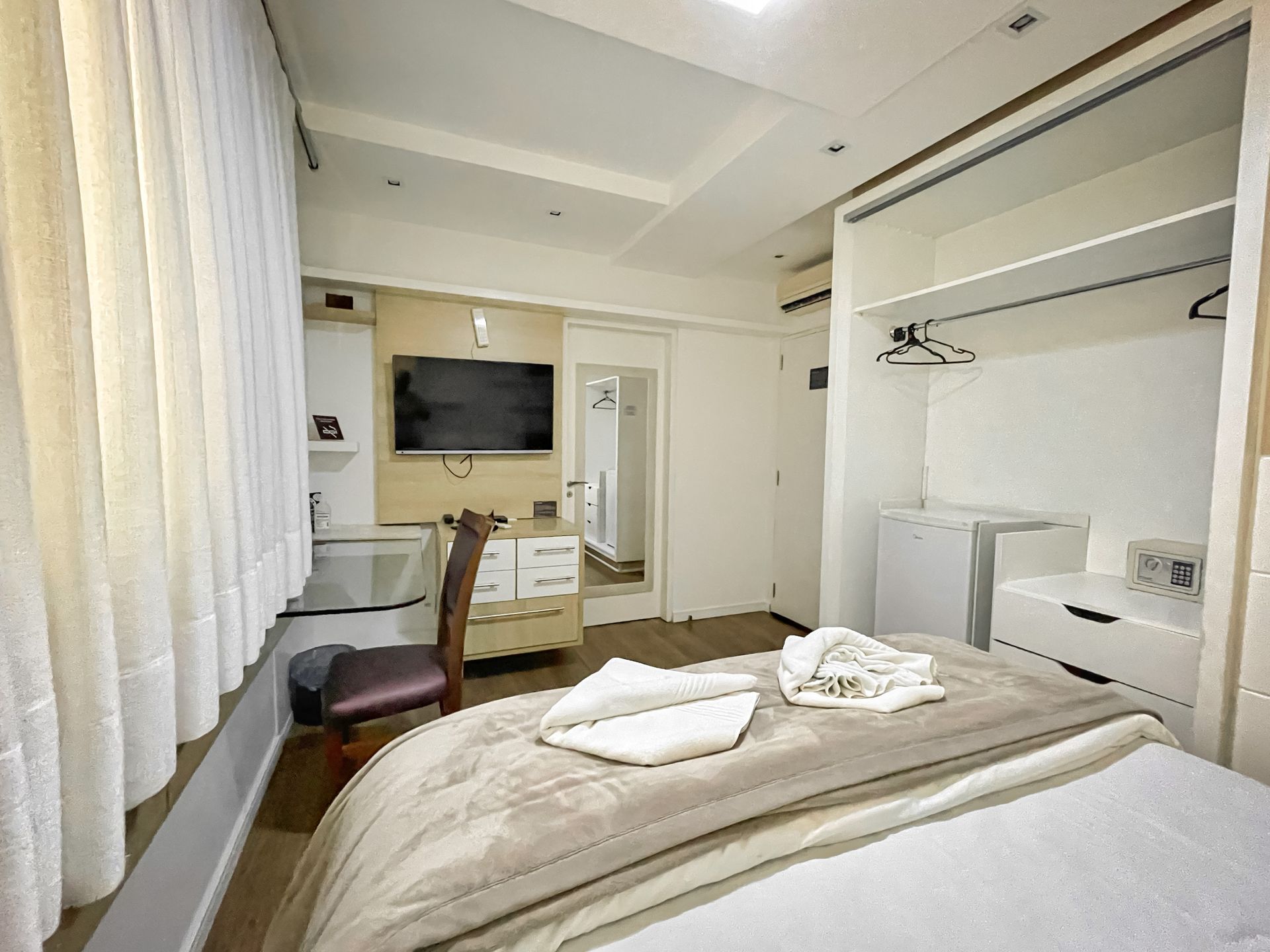 A hotel room with a bed , television , desk and chair.
