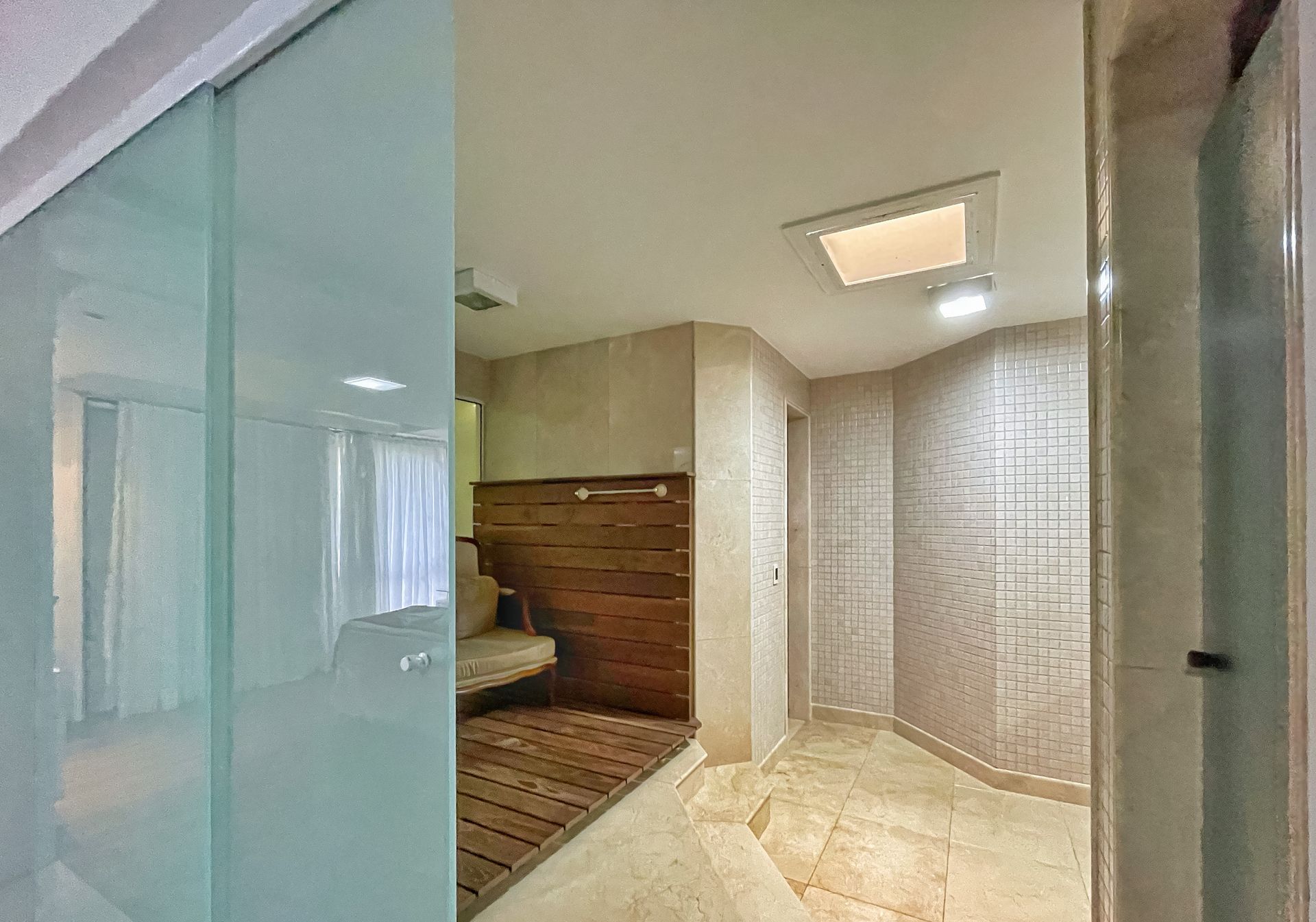 A bathroom with a sliding glass door and a wooden bench.