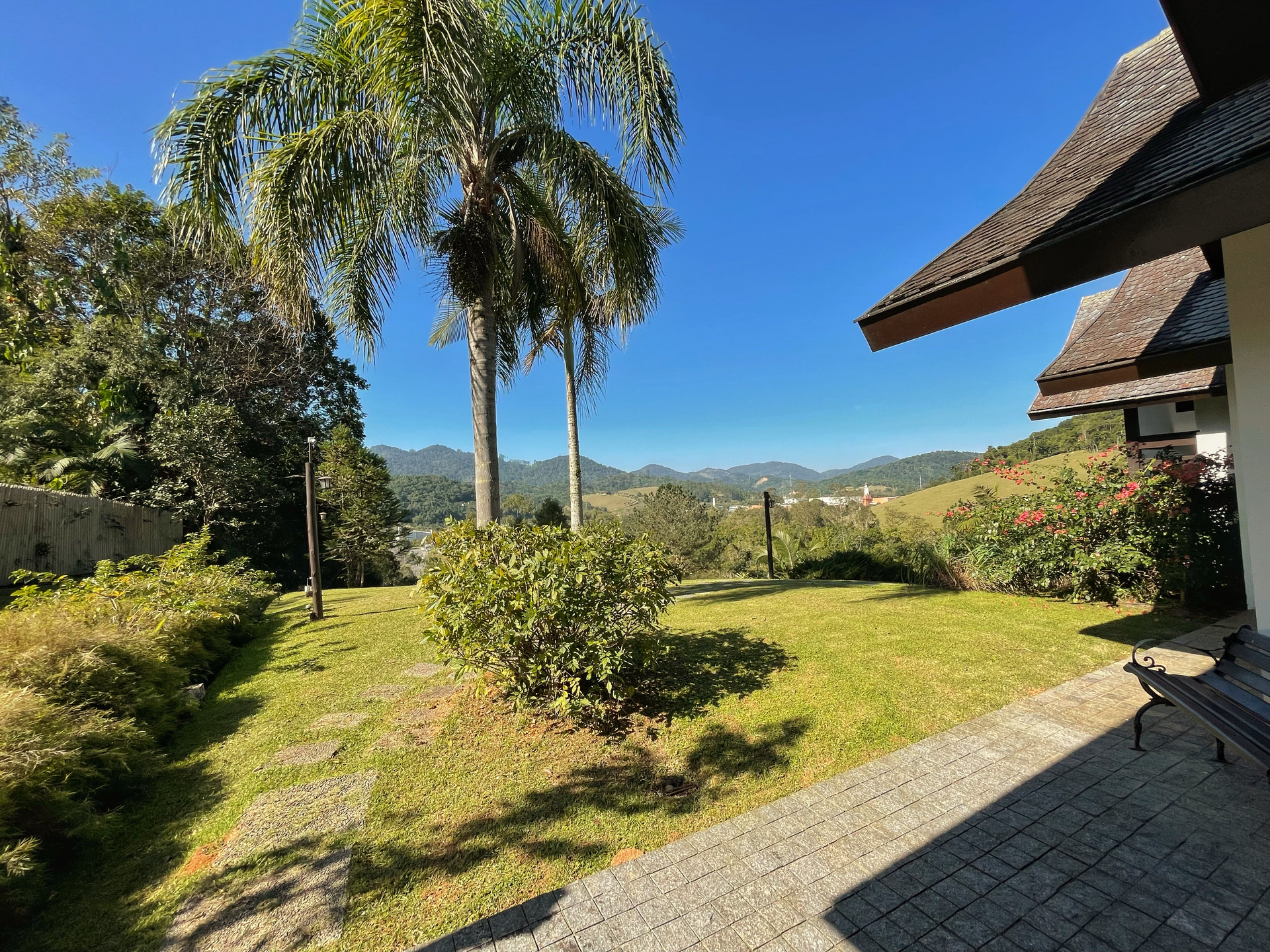 A house with a thatched roof is surrounded by a lush green lawn and trees.