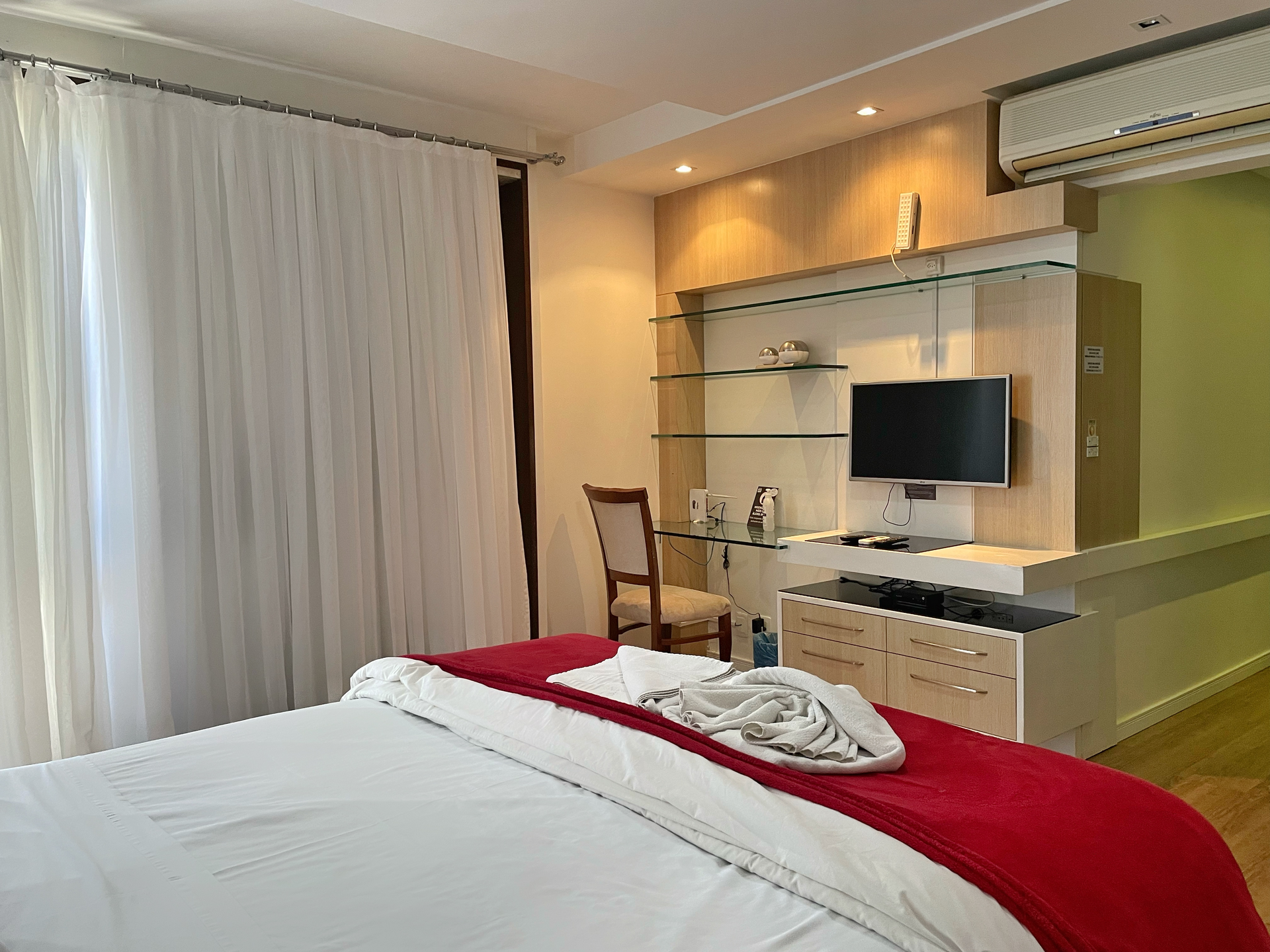 A hotel room with a bed , desk , chair and television.