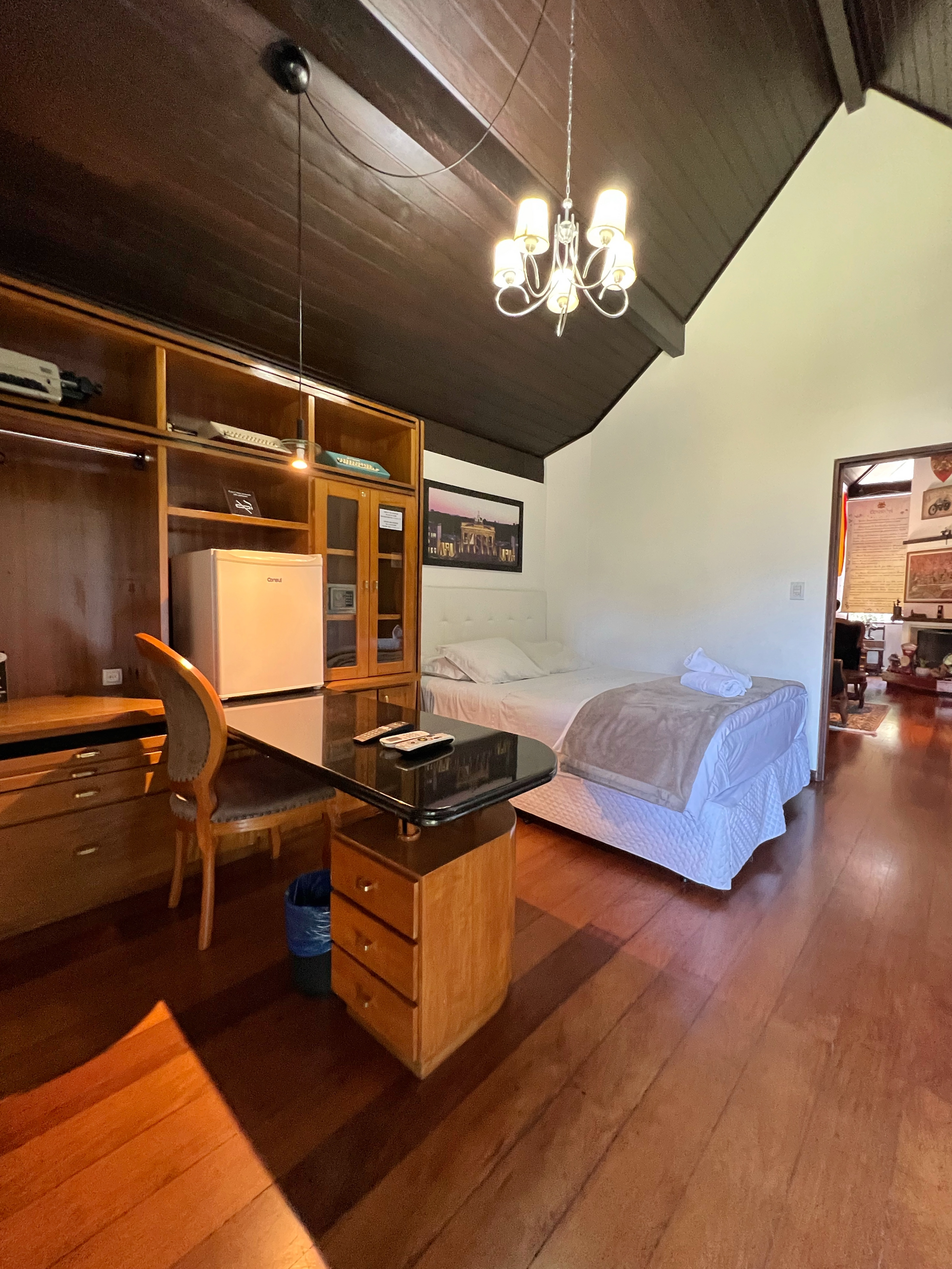 A bedroom with a desk , chairs , a bed and a chandelier.