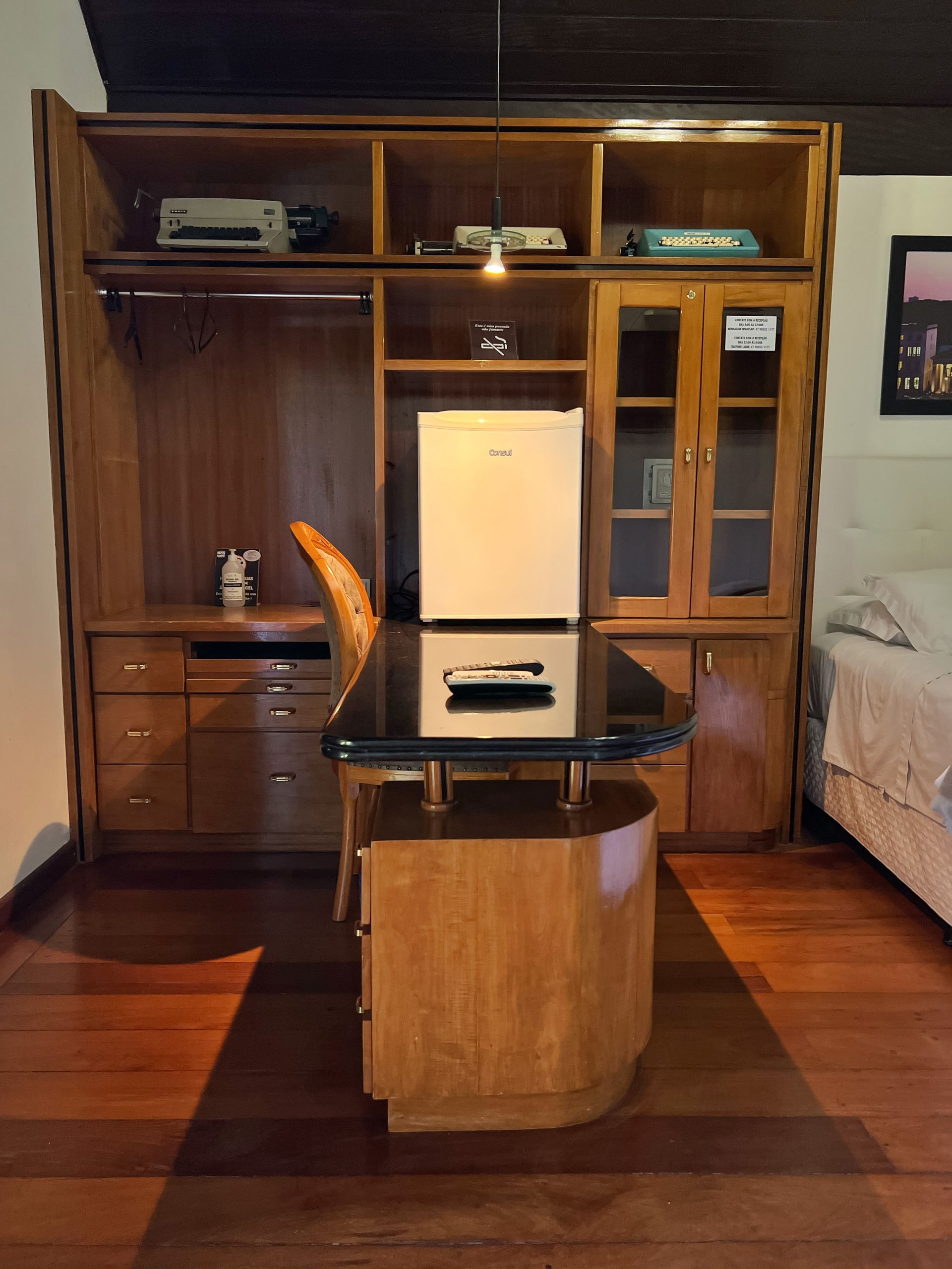 A small fridge sits on top of a desk in a room