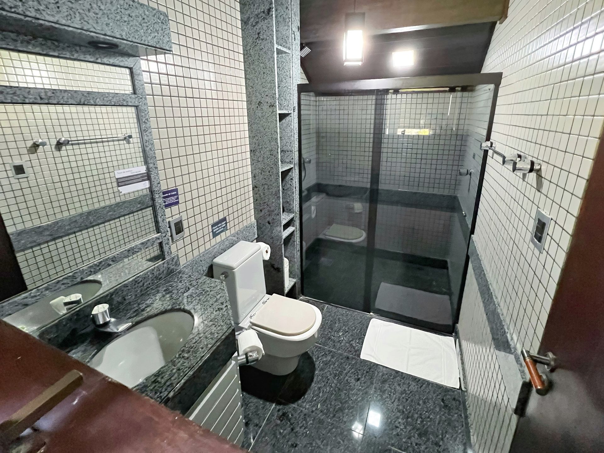 A bathroom with a toilet , sink , mirror and shower.