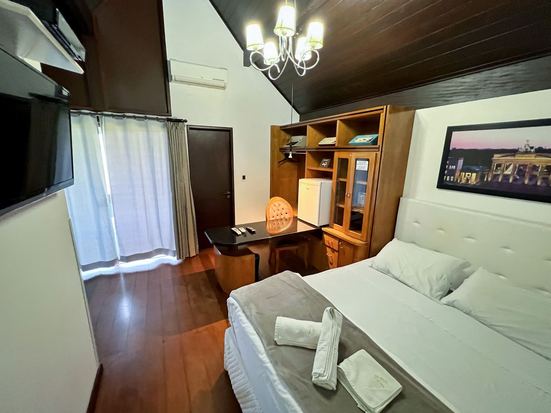 A hotel room with a king size bed , desk , and television.