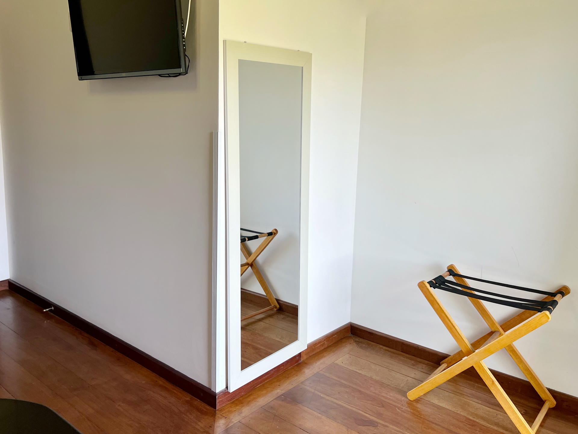A room with a mirror and a tv on the wall