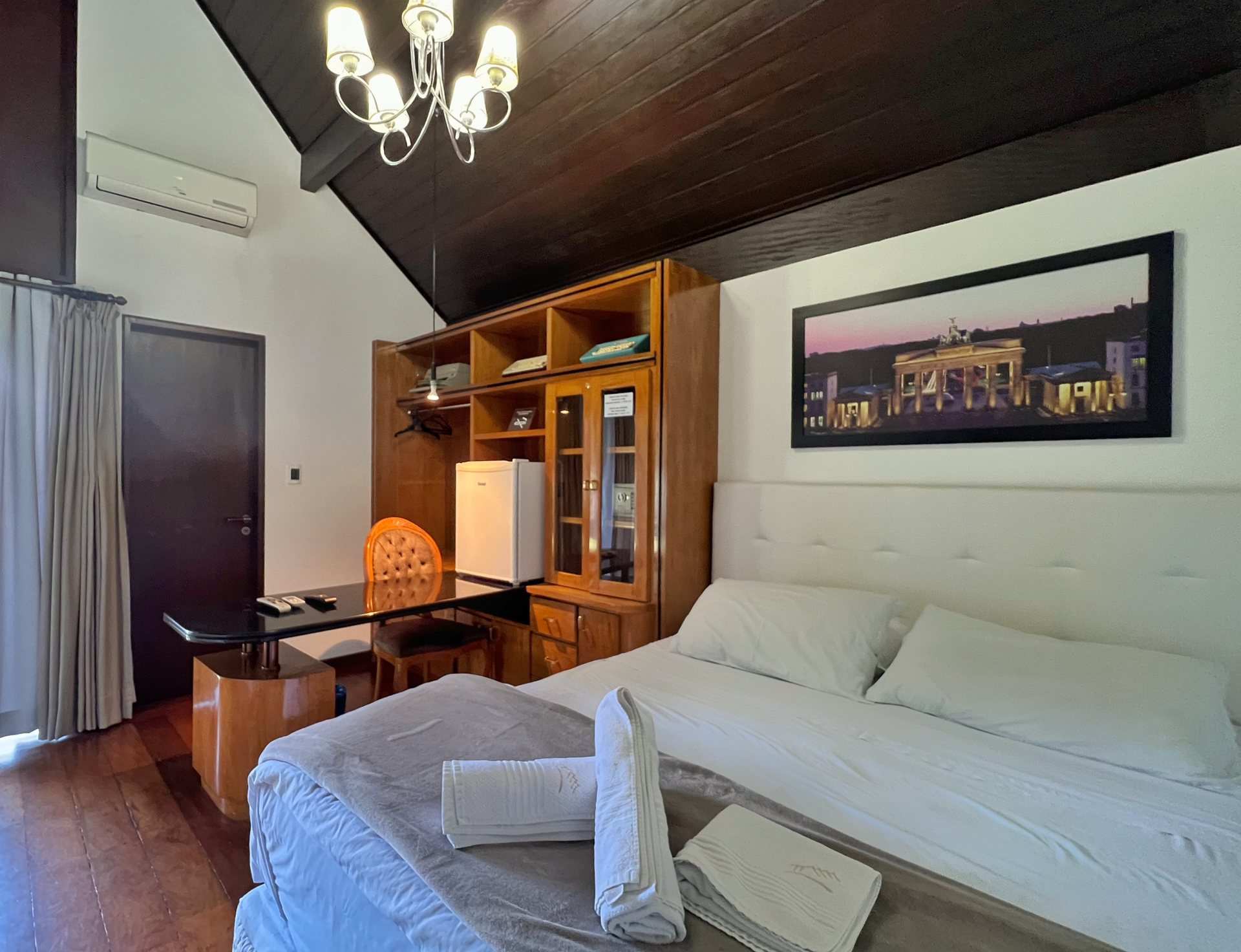 A bedroom with a large bed and a picture on the wall.