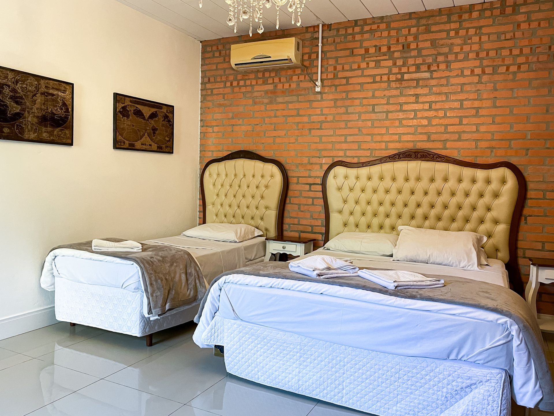 A bedroom with two beds and a brick wall.