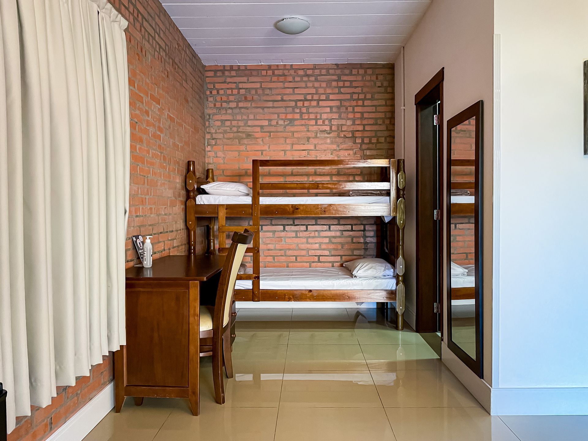 A bedroom with bunk beds , a desk , chairs and a mirror.
