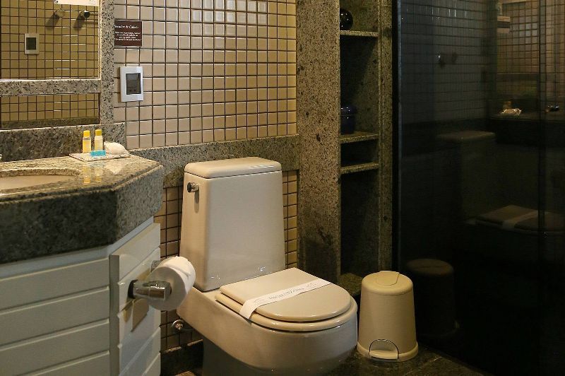 A bathroom with a toilet , sink , mirror and shower.