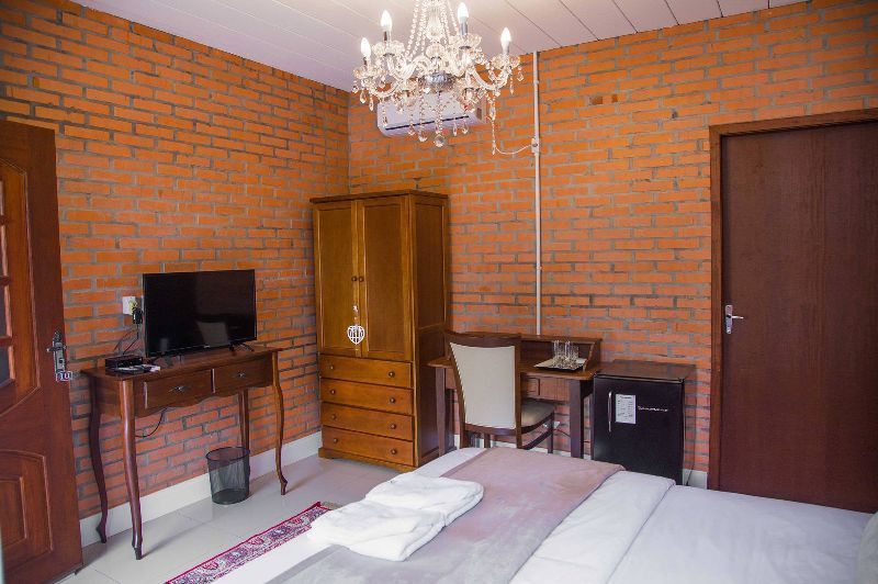 A hotel room with a bed , desk , chair and television.