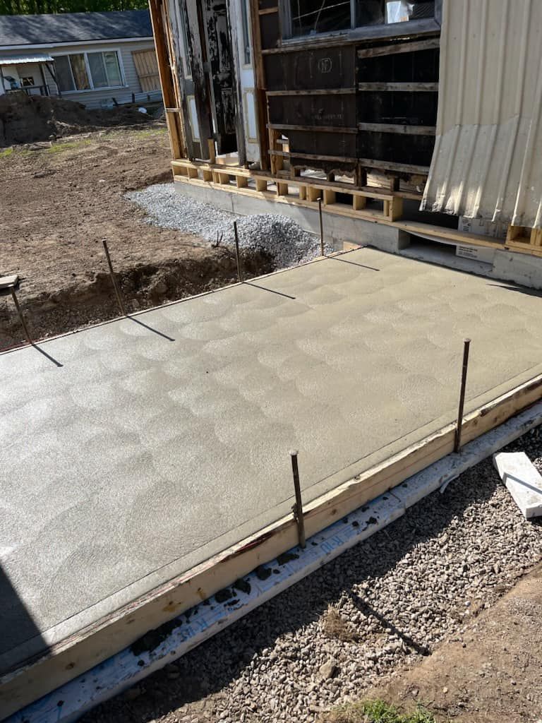 Une allée en béton est en cours de construction devant une maison.