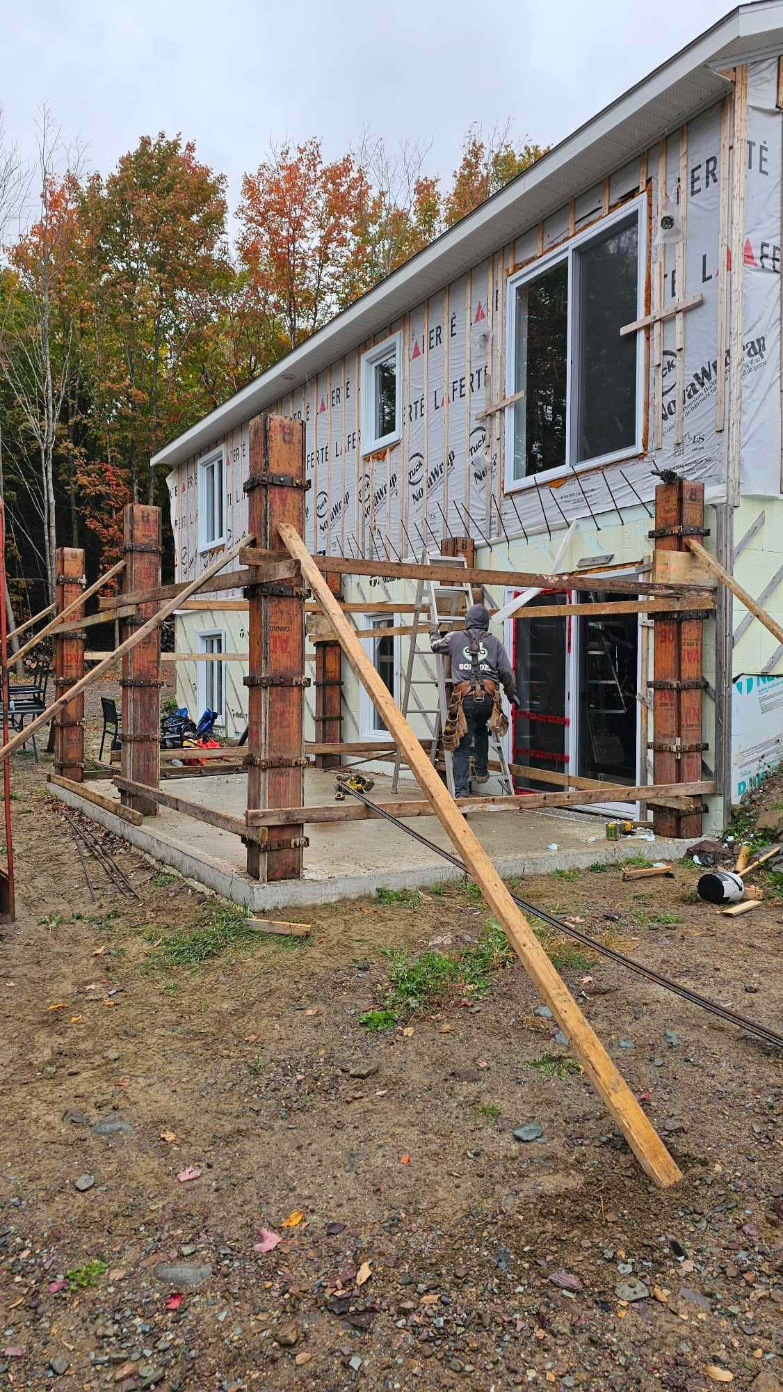 Une maison est en construction au milieu d'un champ de terre.