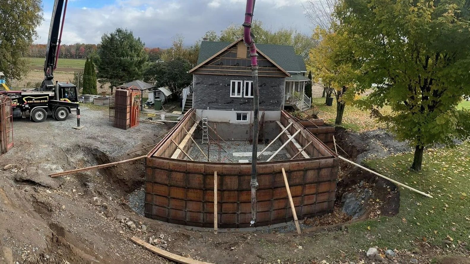Un grand mur de béton est en train d'être construit devant une maison.