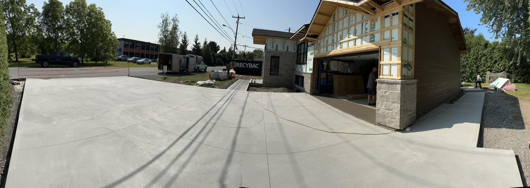 Une vue panoramique d'une maison en construction avec une allée en béton devant elle.