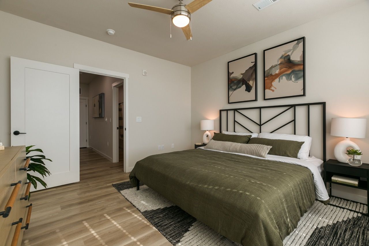Bedroom with king bed, black metal headboard, two nightstands, ceiling fan, and wall art.