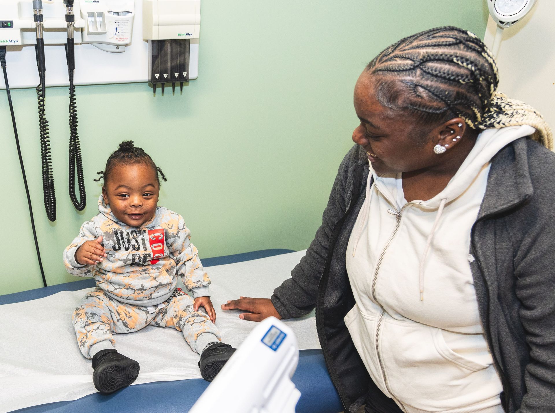 A woman is sitting next to a baby in a hospital bed
