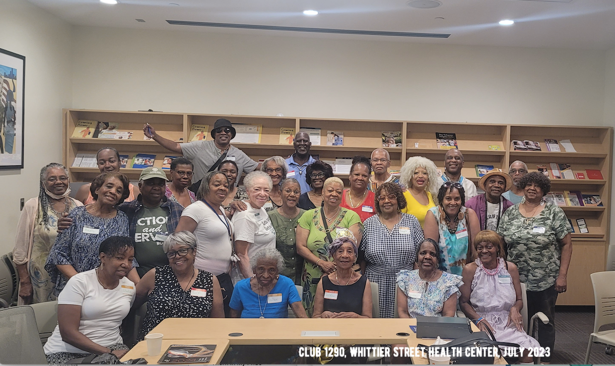 Large group posing in a library with bookshelves and a banner in front
