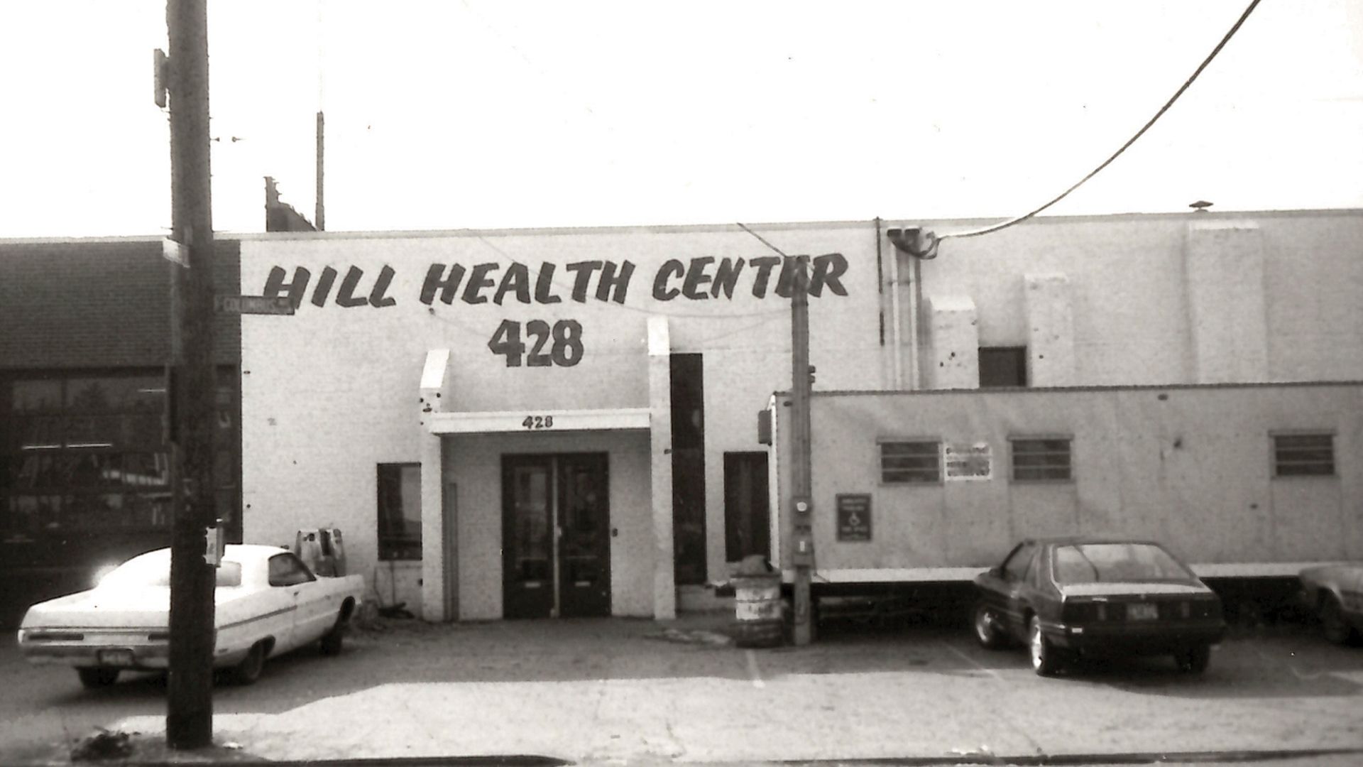 Front view of Jill Health Center 428 with parked cars and a utility pole in front