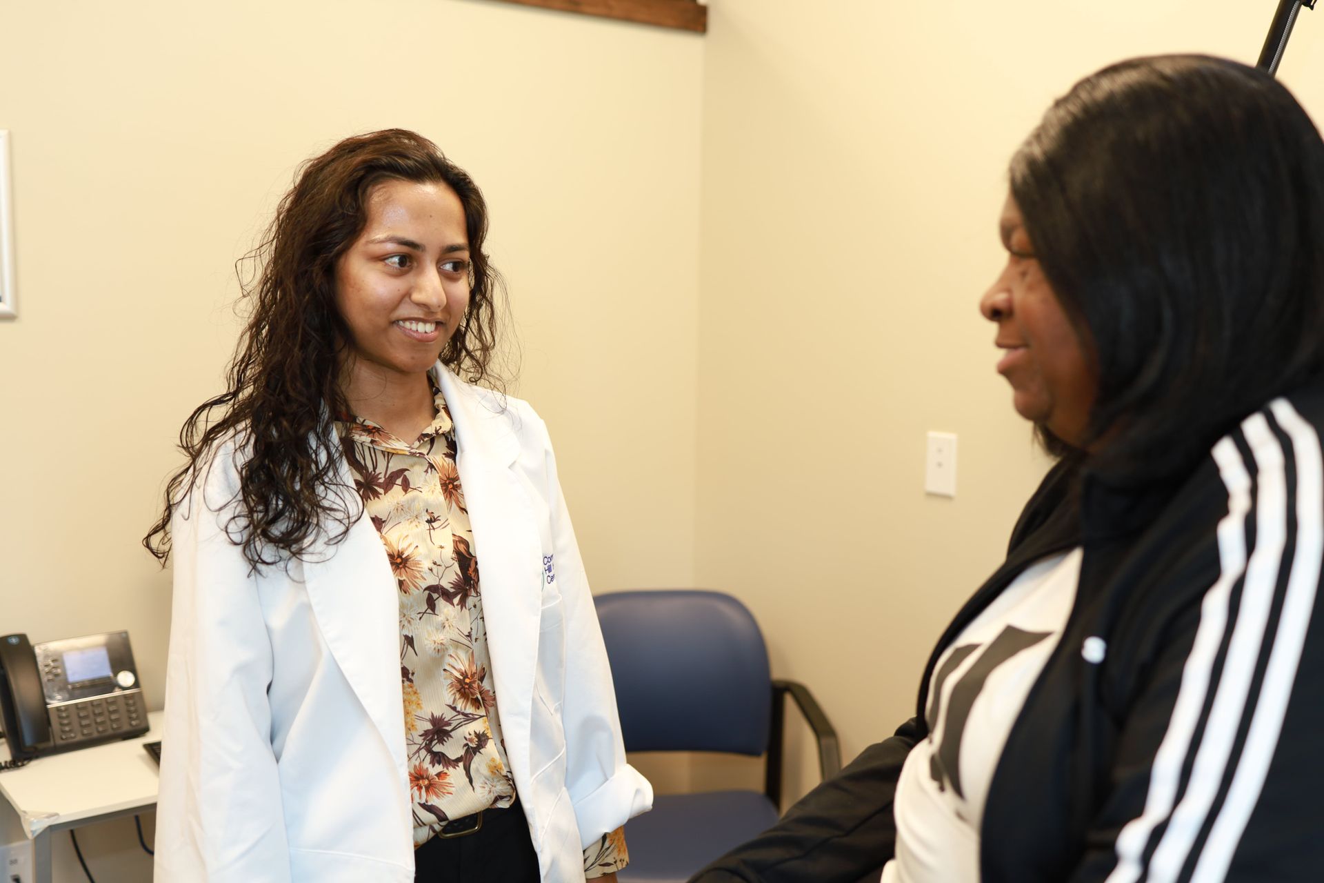 An image of a female doctor and a woman looking at each other in an exam room
