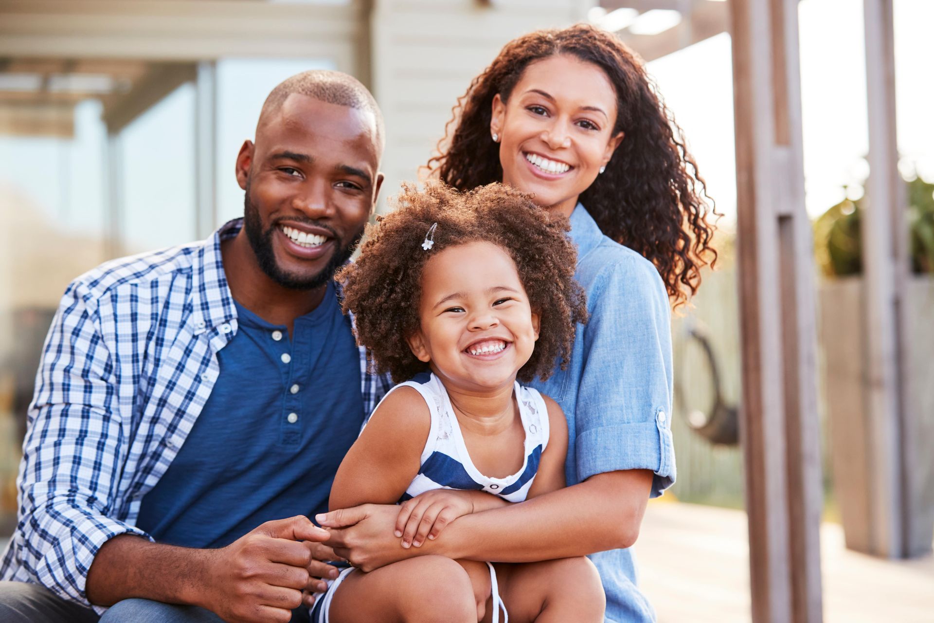A man and woman are sitting on a porch with a little girl