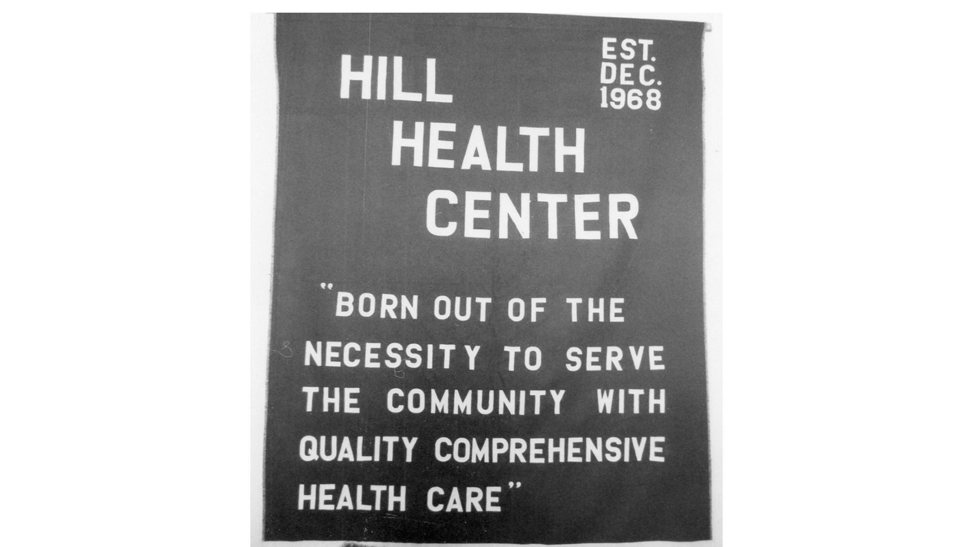 Sign for Hill Health Center with quote about serving the community with quality comprehensive health care