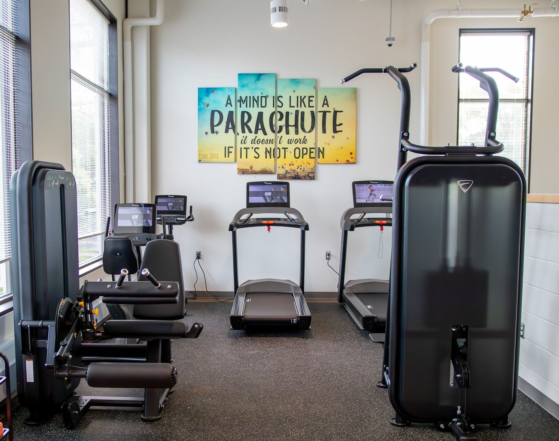 Small gym with exercise machines and a “A Mind Like a Parachute” wall sign