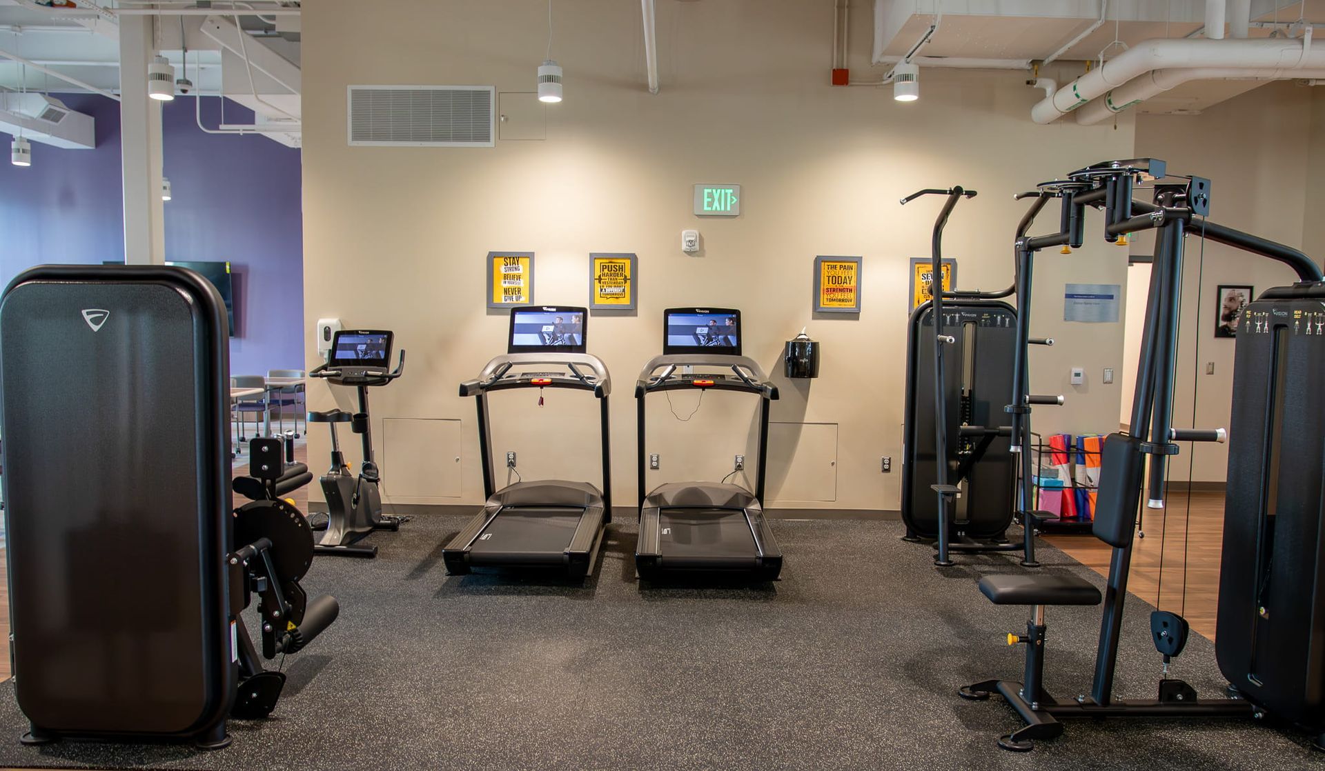 Empty gym with treadmills, weight machines, and exercise equipment on a speckled floor