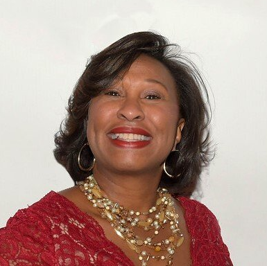 Smiling woman in a red lace top and gold necklace against a white background